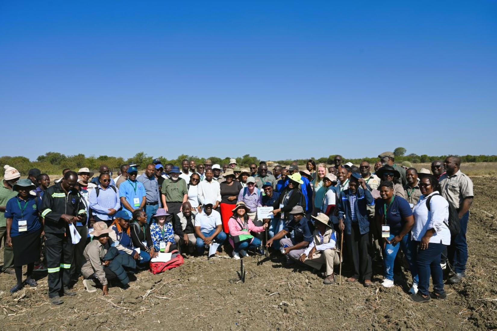 Large group of people posing together in an agricultural field.