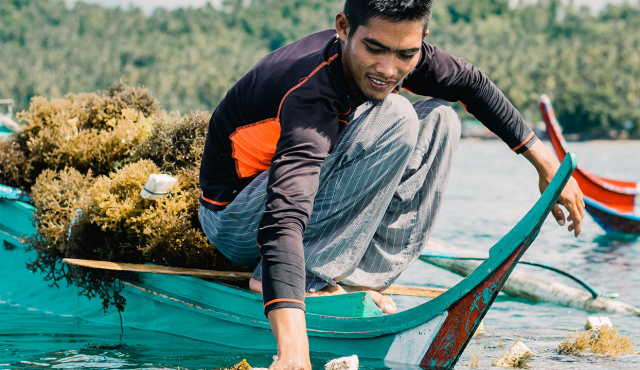 man with seaweed in a small boat