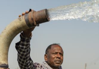 Man holding a water pump that is spraying water