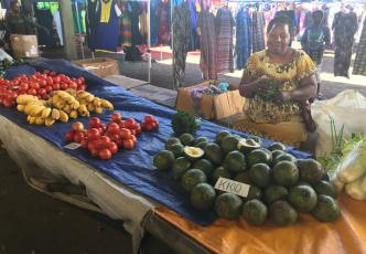 Women sitting at her market stall selling vegetables 