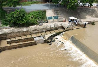 Aerial view of a water control structure and fish passage facility on a river channel.