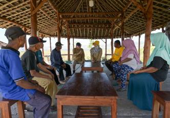 Community members and researchers meeting in an open-sided shelter to discuss local challenges and solutions.