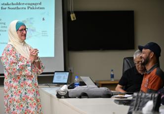 Participant speaking during a workshop while others listen around a meeting table.