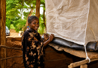 Person standing beside an insect-rearing enclosure covered with mesh fabric.