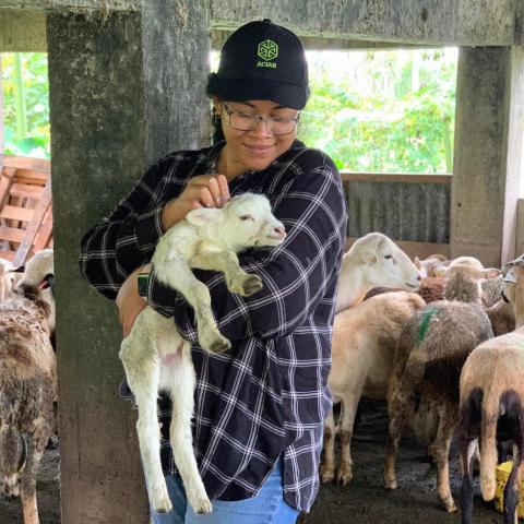 Woman holding a small lamb in her arms