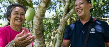 A man and woman hold freshly picked mangoes