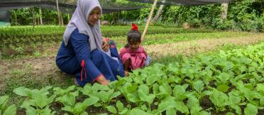 mother and daughter tending crops