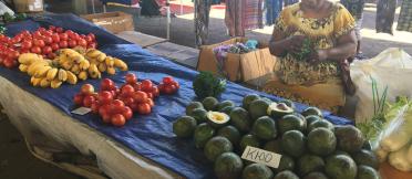 Women sitting at her market stall selling vegetables 