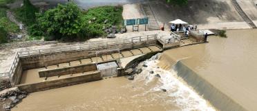 Aerial view of a water control structure and fish passage facility on a river channel.