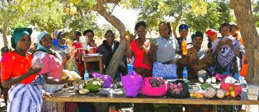 Group of people displaying fresh produce and food products at an outdoor table.