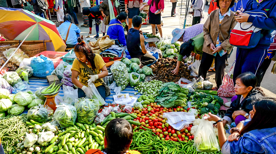 a market showing various types of tomatoes and Asian vegetables