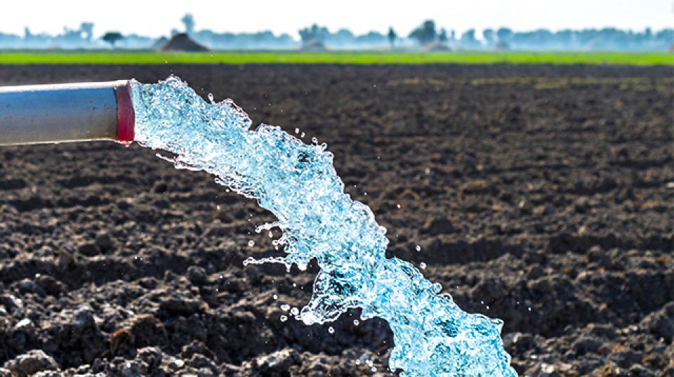 water flows from a pipe over a ploughed field