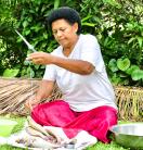 a woman holding a knife, sitting in front of some fish