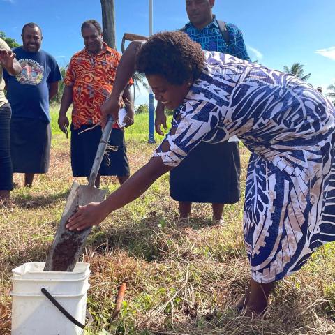 Female farmer shoveling soil into a bucket 