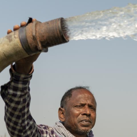 Man holding a water pump that is spraying water