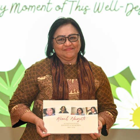Woman holding a book titled Mirah Nuryati