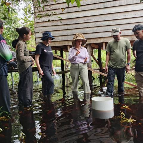 Group of people standing in water around a small structure