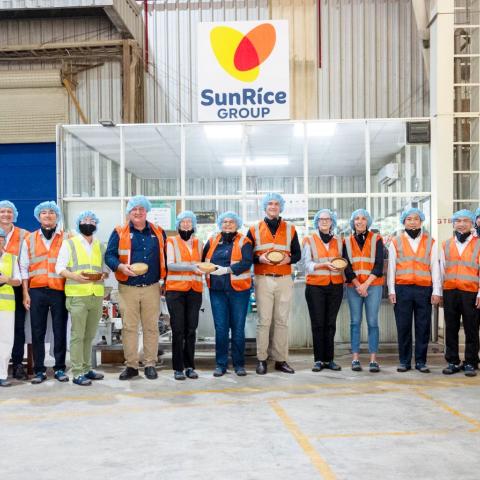 Group of visitors in safety gear standing inside a SunRice Group facility.