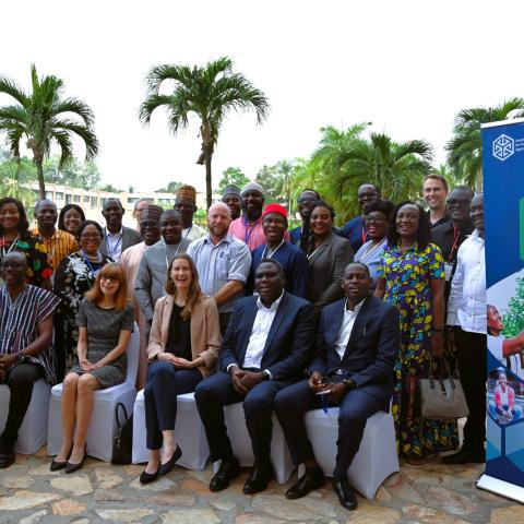 Group of workshop participants seated and standing outdoors beside ACIAR banners.
