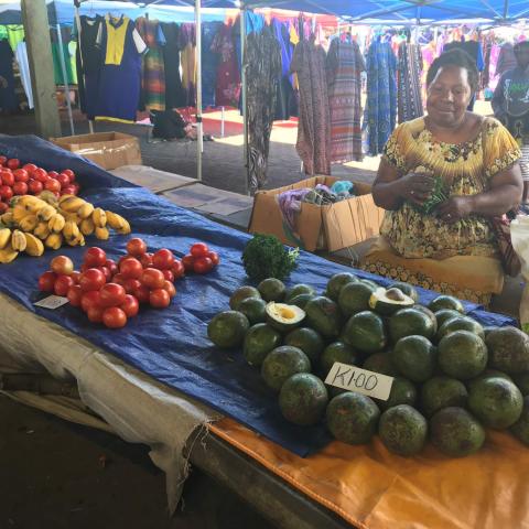 Women sitting at her market stall selling vegetables 