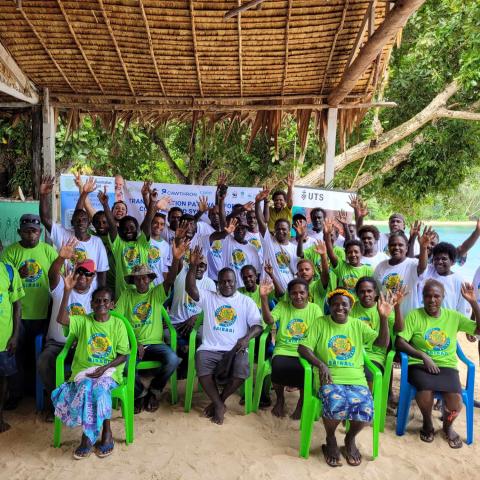 Community group gathered outdoors by the beach during a mangrove conservation workshop