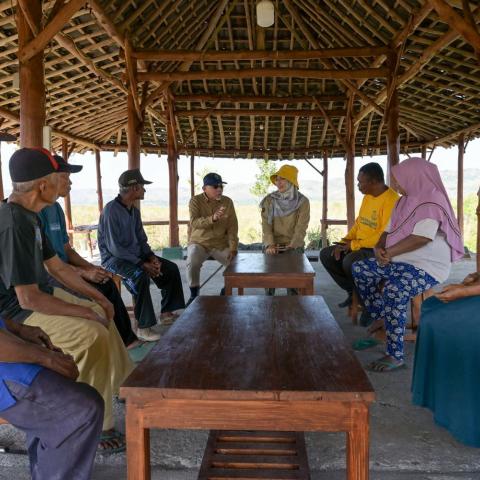 Community members and researchers meeting in an open-sided shelter to discuss local challenges and solutions.