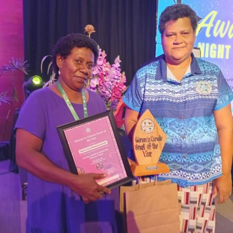 Two females standing side by side with an award