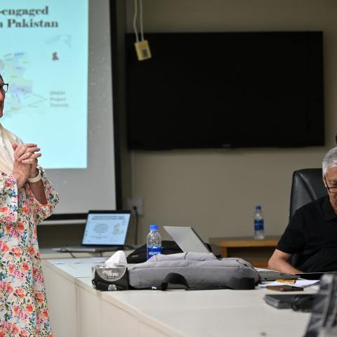 Participant speaking during a workshop while others listen around a meeting table.