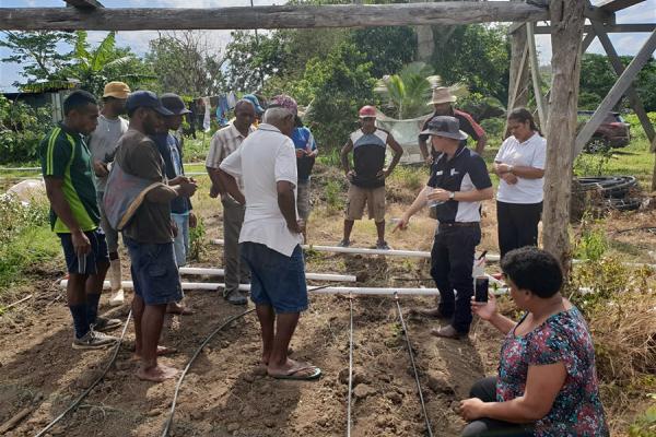 A group of people measuring a structure in a garden