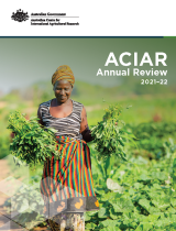 The cover image of the ACIAR Annual Review 21-22 showing a female farmer carrying bunches of freshly harvested vegetables.