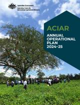 Cover page of the publication, which is a photograph of about 30 people standing beneath a large tree, talking to each other. The tree and people are in a field of low growing green plants.