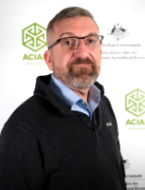 Headshot image of Dr Steven Crimp standing in front of an ACIAR banner.
