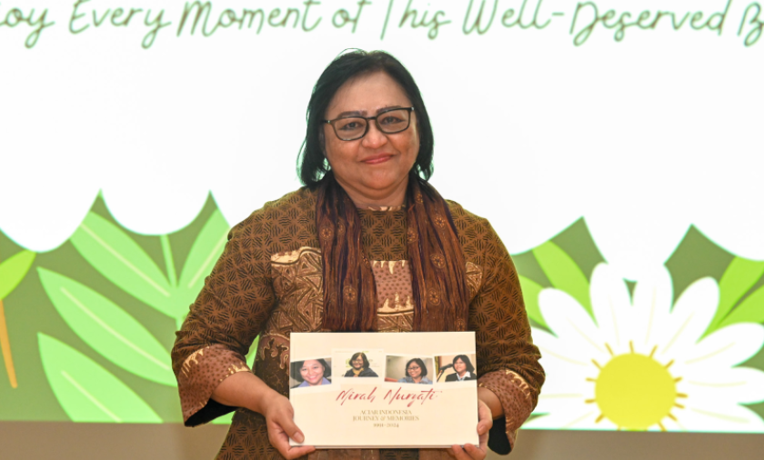 Woman holding a book titled Mirah Nuryati