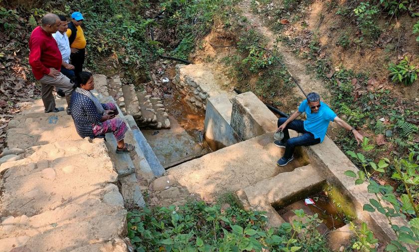 A group of people sitting outside on spring water infrastructure