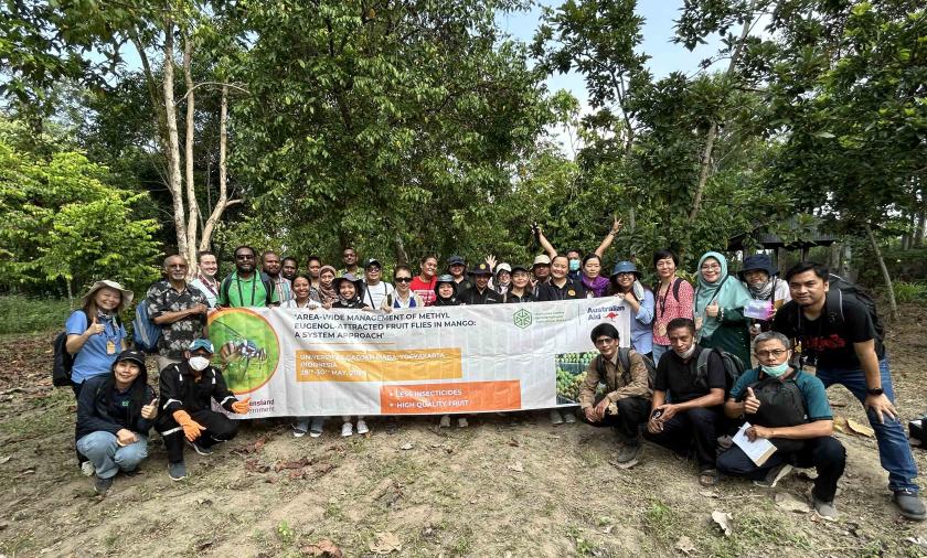 Group of people outside holding a large project sign
