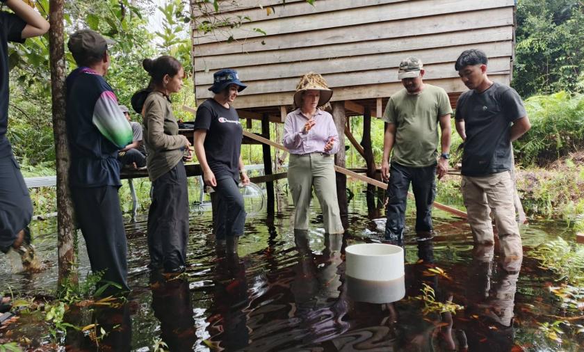Group of people standing in water around a small structure