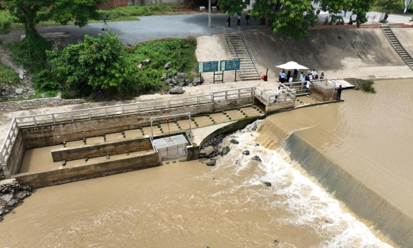 Aerial view of a water control structure and fish passage facility on a river channel.