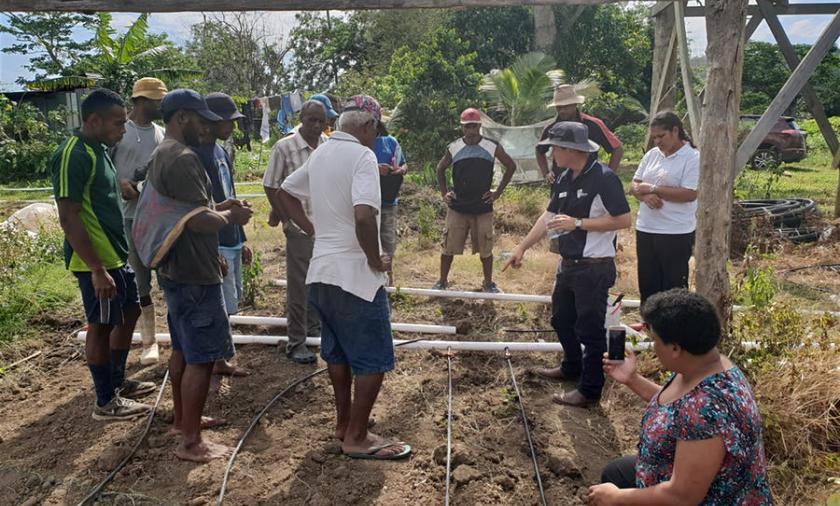 A group of people measuring a structure in a garden