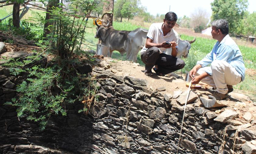 Men kneeling beside a well